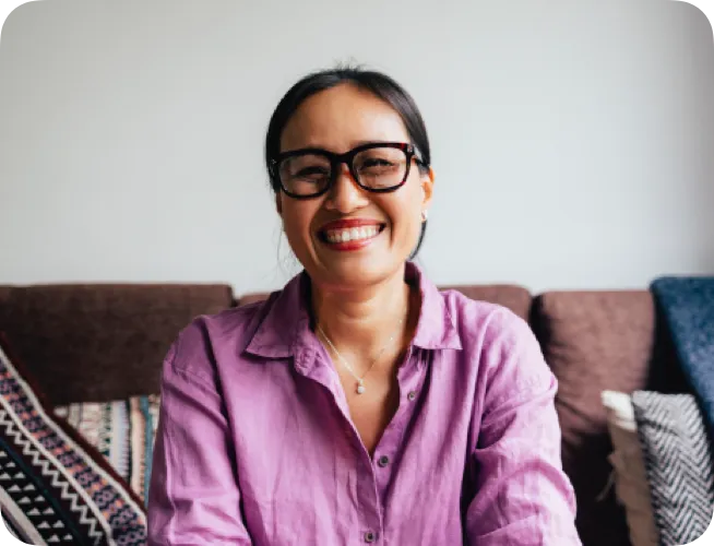 Woman in her forties sitting on couch smiling